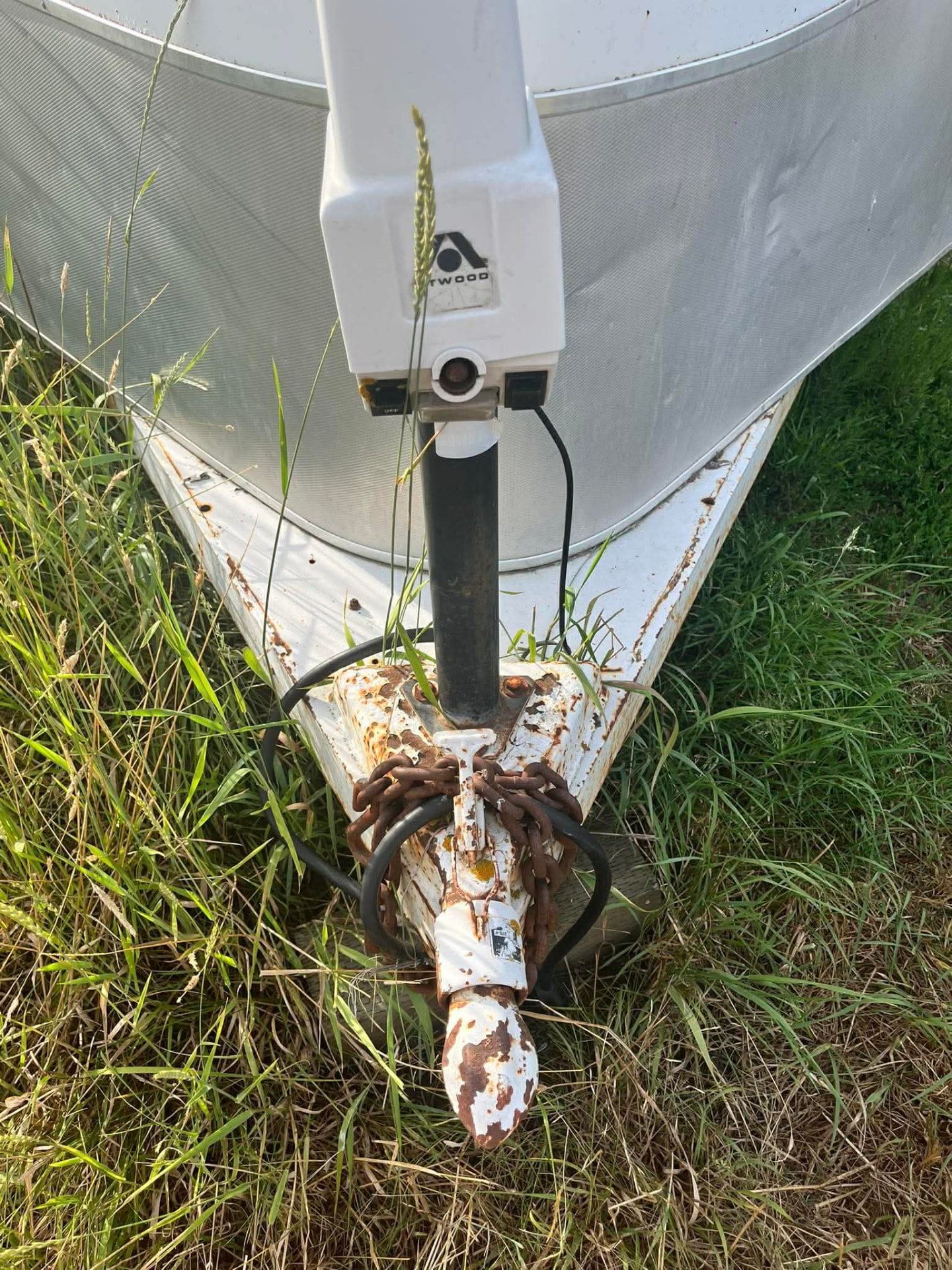 Rusty white trailer tongue with a worn coupler and jack before replacement